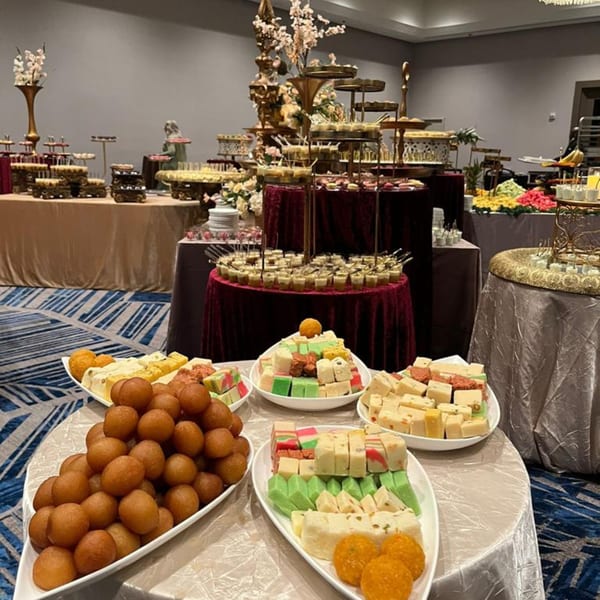 A lavish Pakistani dessert buffet with gulab jamun, barfi, and other sweets on display.