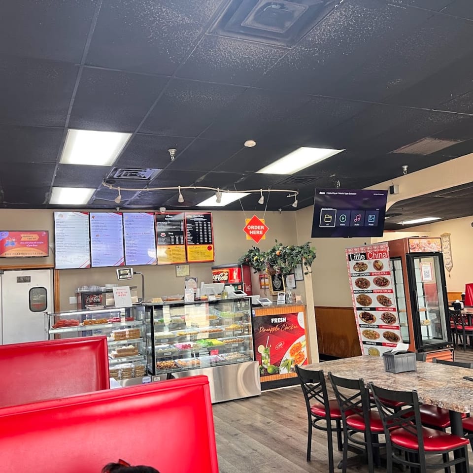 Interior of Chaat House, showing red booths, display cases with food, and menu boards.