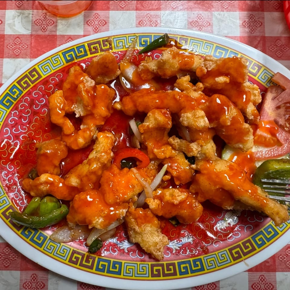 Sweet and sour chicken with peppers and onions on a decorative plate at Chaat House.