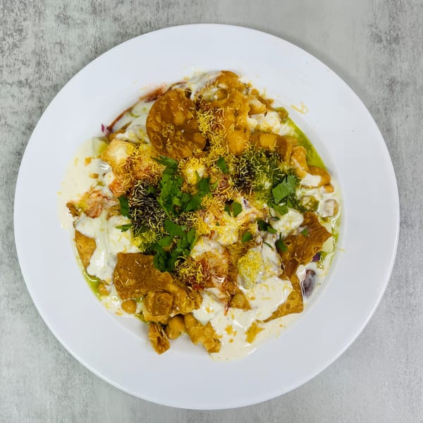 Chaat House's Pakistani chaat, a vibrant dish with crispy elements, sauces, and fresh herbs on a white plate.