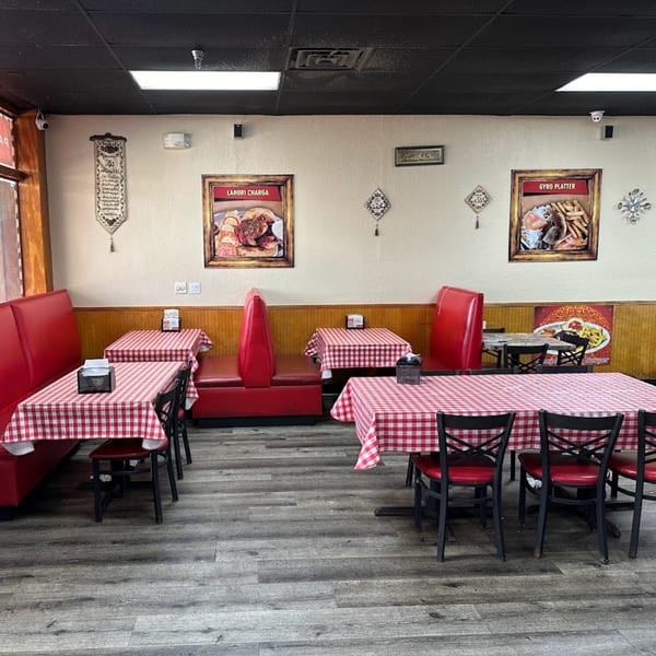 Interior of Chaat House with red booths, checkered tablecloths, and Pakistani food posters on light walls.