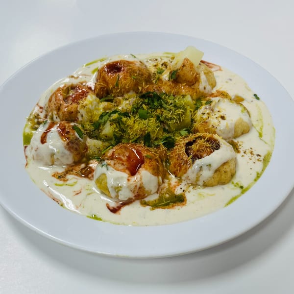 A white plate holds Chaat House's dahi bhalla, a Pakistani dish with yogurt, chutneys, and spices.